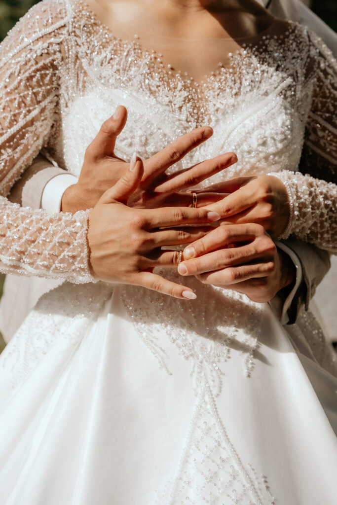 Detailfoto van de trouwringen die het bruidspaar om de vinger schuift bij elkaar met mooie nagelstyling