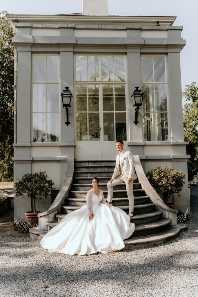 Bruid zit in romantische en moderne trouwjurk bij landhuis tijdens de fotoshoot